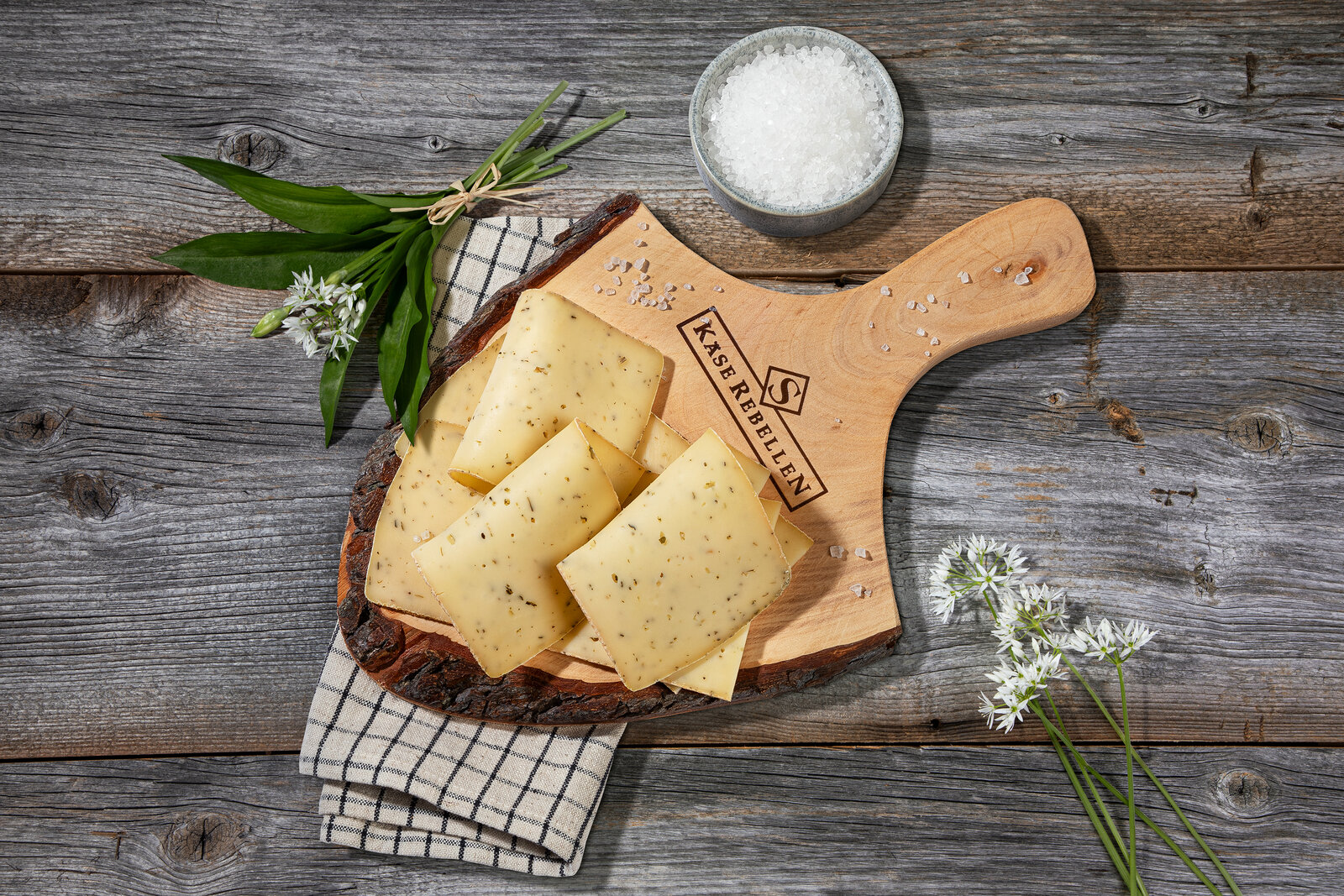 Leckerer Bärlauch Scheibenkäse auf einem urigen Holzbrett hingelegt.