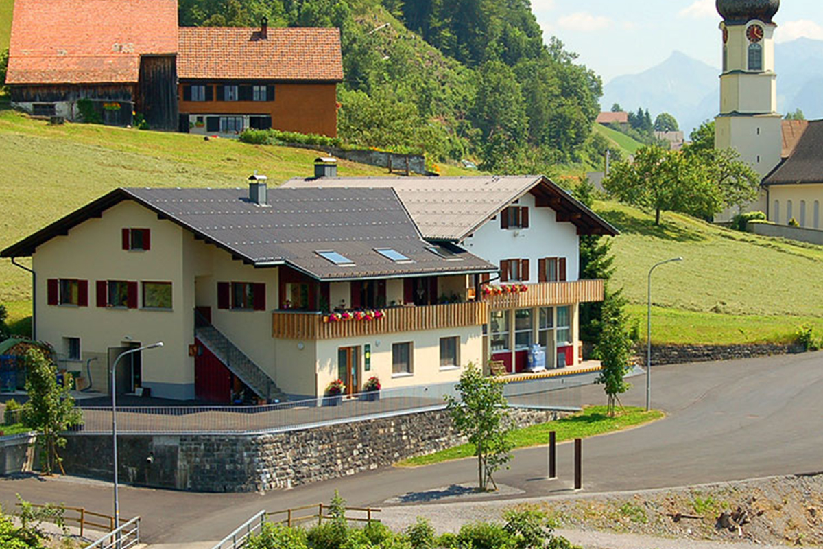 Thüringerberg. Haus mit einer Kirche im Hintergrund.